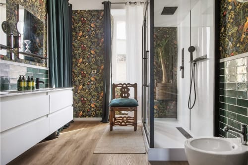 Salle de bain luxueuse à Alombre B&B à Lectoure avec papier peint fleuri, meuble vasque blanc, accents carrelage vert et douche spa.