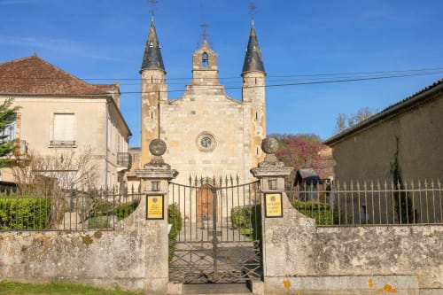Le gîte Alombre à Lectoure : une charmante église en pierre aux trois clochers derrière des grilles en fer