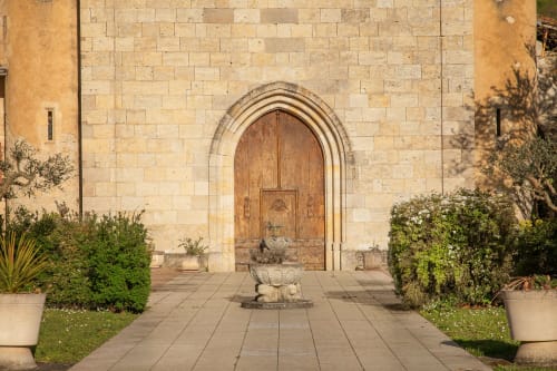 Entrée de la maison d'hôtes Alombre à Lectoure, France - porte en bois voûtée sur façade en pierre avec cour intérieure et plantes en pots