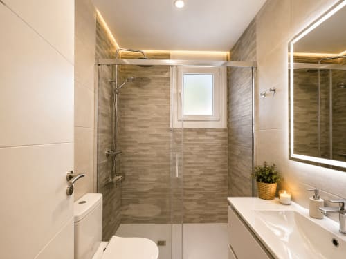 Baño moderno en apartamento Holibai en Baiona con ducha a ras de suelo, espejo iluminado y lavamanos blanco