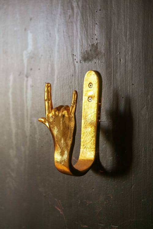 Gold hand gesture hook mounted on concrete wall at Alombre B&B in Lectoure, France