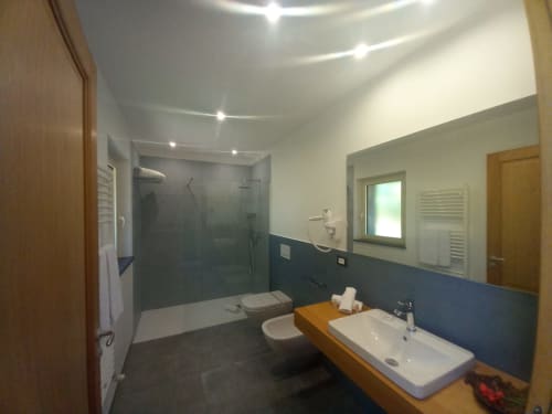 Modern bathroom at Agriturismo Lumia Resort in Riposto with shower, toilet, and wooden vanity
