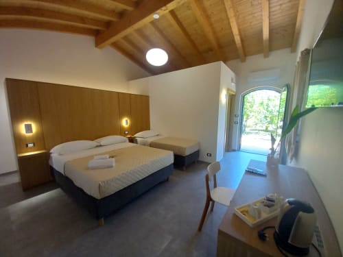 Modern triple bedroom at Agriturismo Lumia Resort in Riposto with wooden ceiling, twin beds, and patio access