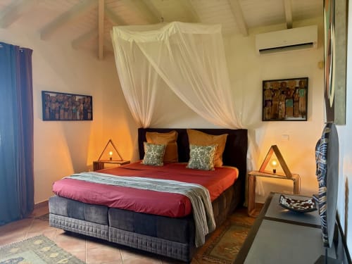 Chambre luxueuse de villa caribéenne avec lit à baldaquin, éclairage chaleureux et vue sur mer à LÉZILÉ CONCIERGERIE, Bouillante
