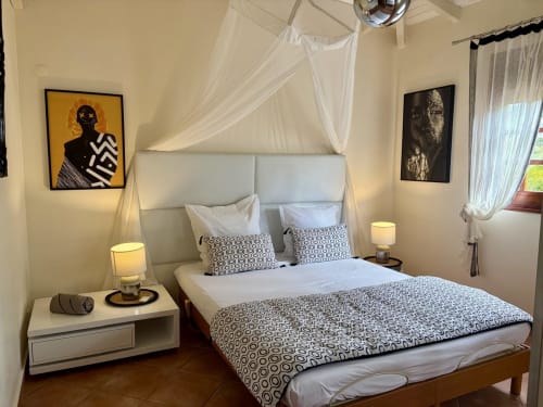 Chambre élégante à la villa LÉZILÉ Conciergerie à Bouillante avec lit à baldaquin, vue sur mer et décoration moderne