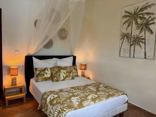Chambre tropicale à la villa LÉZILÉ avec décor de palmiers, vue mer, éclairage chaleureux et mobilier d'inspiration caribéenne