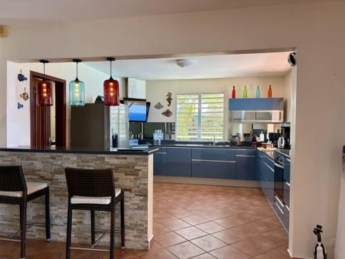 Cuisine moderne avec armoires bleues, coin bar et luminaires suspendus à Villa Bell'ô, Bouillante Guadeloupe