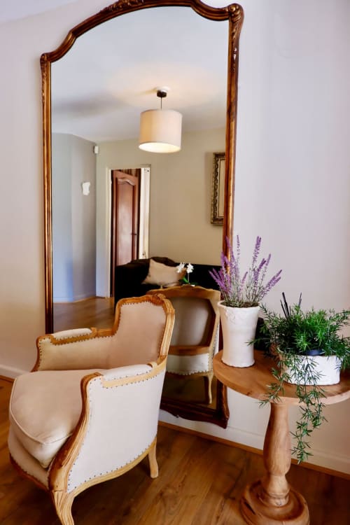 Zone de détente élégante de la suite Bastide Aïna avec miroir orné, fauteuils tapissés crème, plante de lavande et table en bois