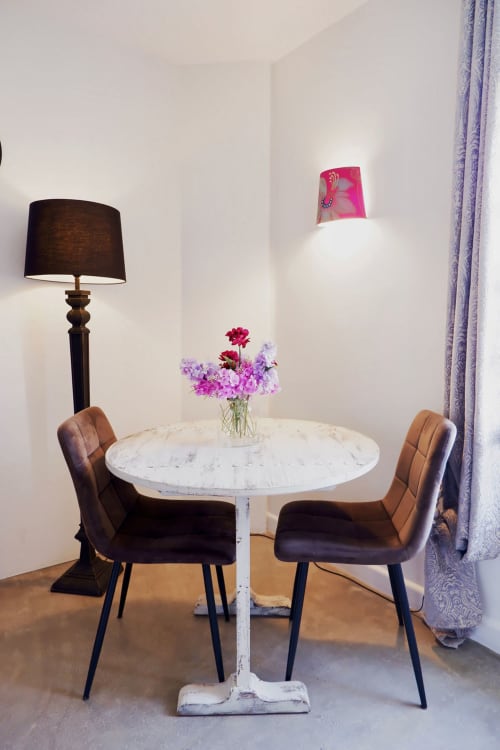 Table ronde en marbre, chaises en velours marron, fleurs roses fraîches et lampadaire noir dans la suite Bastide Aïna à Grasse