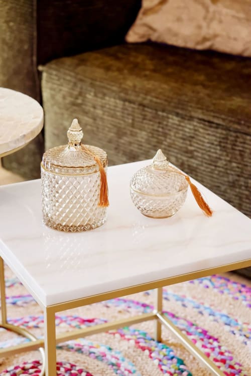 Deux vases décoratifs en cristal aux finitions dorées et pompons orange sur table blanche, suite Bastide Aïna, Grasse