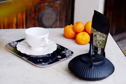 Mise en place élégante à la Bastide Aïna : tasse blanche, agrumes et vase noir décoratif à Grasse