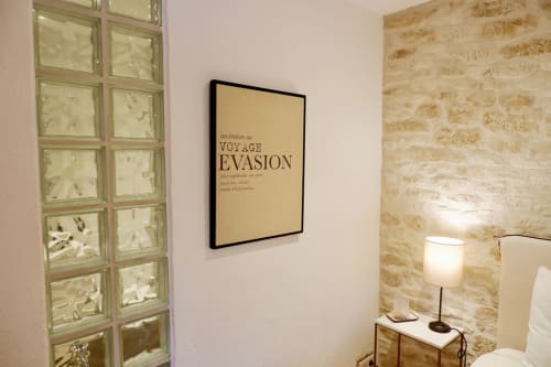 Chambre de la Bastide Aïna à Grasse avec murs en pierre, texte français encadré et éclairage décoratif