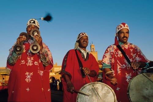 Musiciens marocains traditionnels en robes rouges ornées se produisant au Riad Eucalyptus, hôtel ethnique à El Ghazouane, avec instruments en cuivre