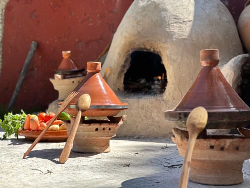 Tajines traditionnels avec cuillères en bois devant le four en terre du Riad Eucalyptus à El Ghazouane, Maroc