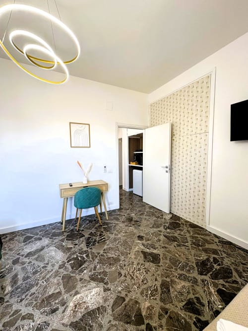Camera moderna dell'hotel Newhouse Bari con pavimento in marmo, scrivania in legno, sedia teal e lampada a spirale contemporanea