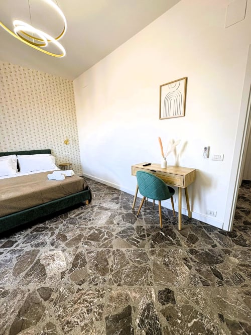 Camera Deluxe Cavour dell'hotel Newhouse Bari con pavimenti in marmo, scrivania in legno con sedia turchese e moderni comfort