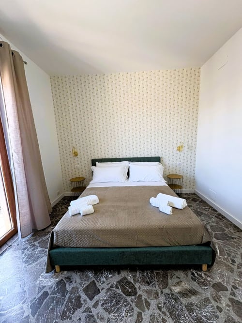 Camera Deluxe dell'hotel Newhouse Cavour a Bari con letto verde, carta da parati decorata e balcone con vista sulla città