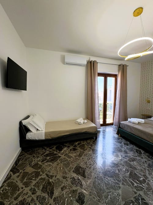 Camera Cavour Deluxe 2 presso Newhouse hotel a Bari con due letti, pavimento in marmo, balcone, aria condizionata e TV a schermo piatto