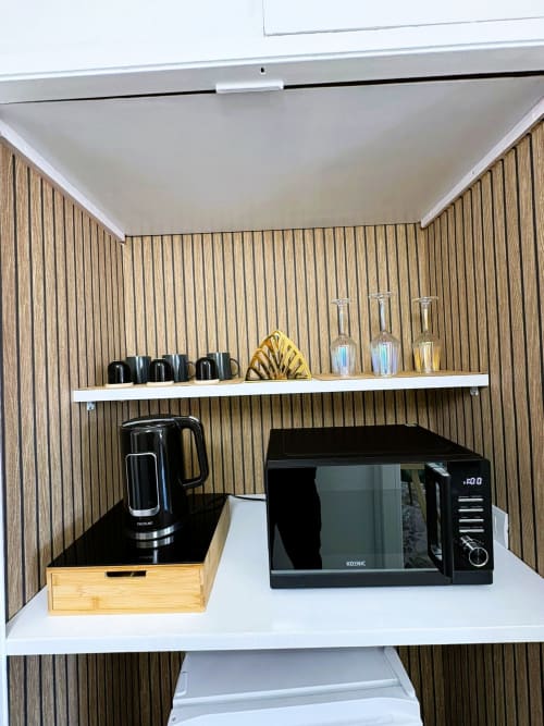 Angolo cottura moderno nella camera Newhouse Cavour Deluxe a Bari, con forno a microonde nero, bollitore elettrico, bicchieri e