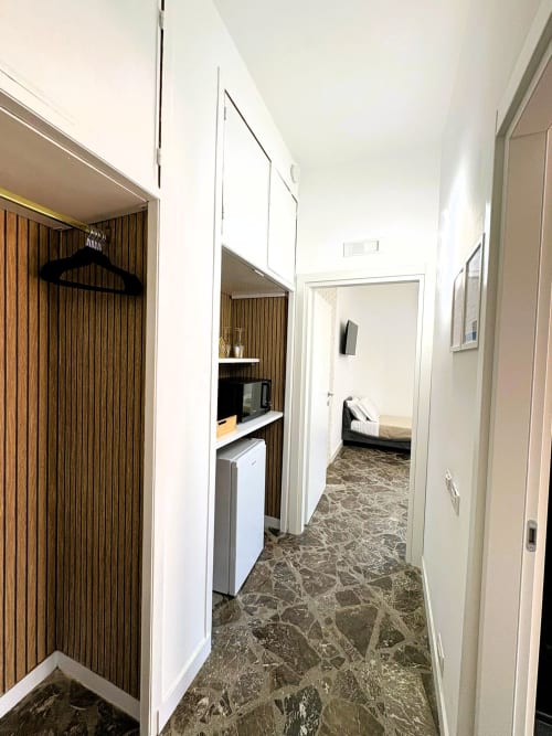 Corridoio moderno della suite Cavour Deluxe presso l'hotel Newhouse Bari, con mobili bianchi, angolo cottura, pavimento in marmo e