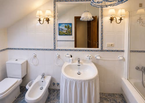 Elegante baño de la villa As Landras en HoliBai, Baiona, España con azulejos azules y blancos, lavabo redondo y vistas al río