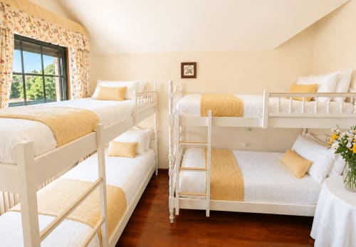 Dormitorio luminoso con literas blancas, detalles amarillos y vista al río en la villa As Landras Tomiño. Galicia