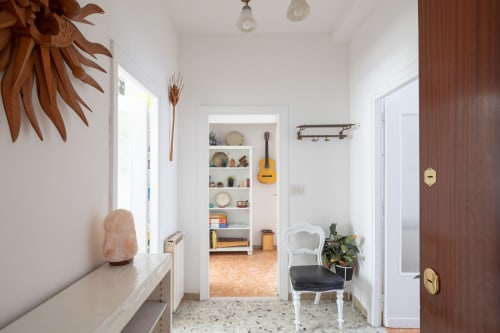 Luminoso corridoio della Stella Polare Luxury Home a Ostia con porte bianche, chitarra decorativa, piante in vaso e arredamento moderno
