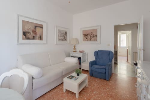 Stella Polare Luxury Home living room in Ostia with beige sofa, blue armchair, framed artwork, and modern furnishings