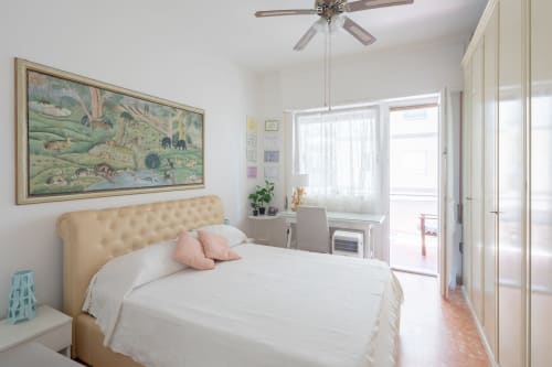 Bright bedroom in Stella Polare Luxury Home, Ostia with cream upholstered bed, white linens, and balcony access