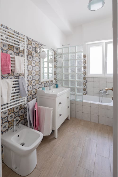 Modern bathroom at Rome Sensorial Rooms in Ostia with patterned tiles, white vanity, toilet, and shower enclosure