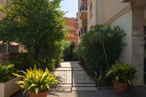 Lush garden courtyard at Rome Sensorial Rooms in Ostia with tropical plants, palm trees, and terracotta pots