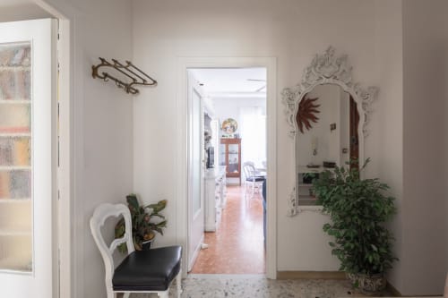 Elegant hallway in Stella Polare Luxury Home, Rome Sensorial Rooms, Ostia. White chair, decorative mirror, potted plants, and