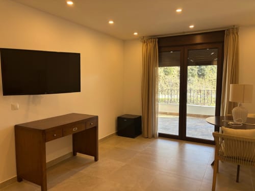 Suite Terraza Río at Hotel Mulhacén Trevélez with TV, desk, and river-view balcony doors in Granada