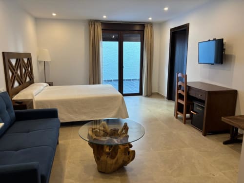 Spacious hotel room with sea view balcony, bed, blue armchair, and wood table at Hotel Mulhacén Trevélez