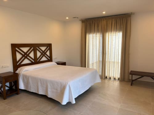 Spacious bedroom at Hotel Mulhacén Trevélez with wooden X-frame bed, white linens, and terrace doors
