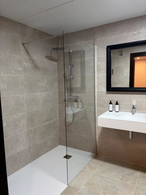 Modern bathroom with walk-in shower, white sink, and beige tile at Hotel Mulhacén Trevélez, Granada