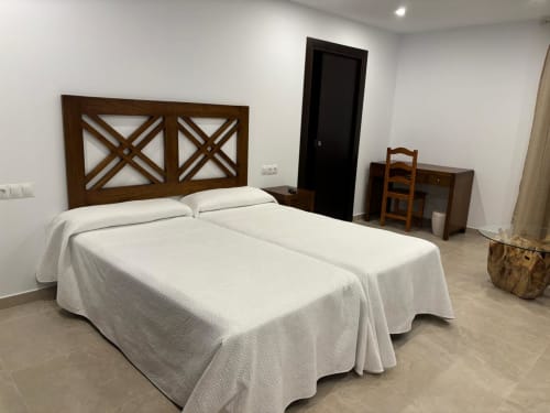 Twin beds with white linens and wooden X-pattern headboard at Hotel Mulhacén Trevélez, Granada