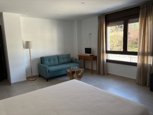 Doble Superior room at Hotel Mulhacén Trevélez with bed, teal sofa, TV desk, and mountain views from balcony