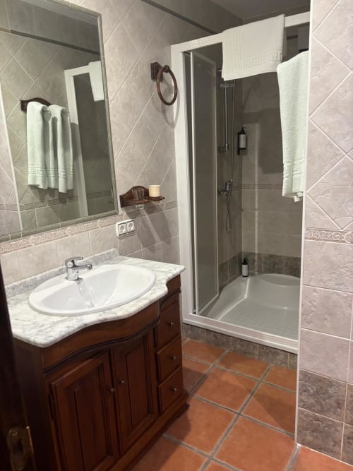 Baño moderno con lavabo de mármol, ducha de cristal y suelo de baldosa de barro en Hotel Mulhacén Trevélez