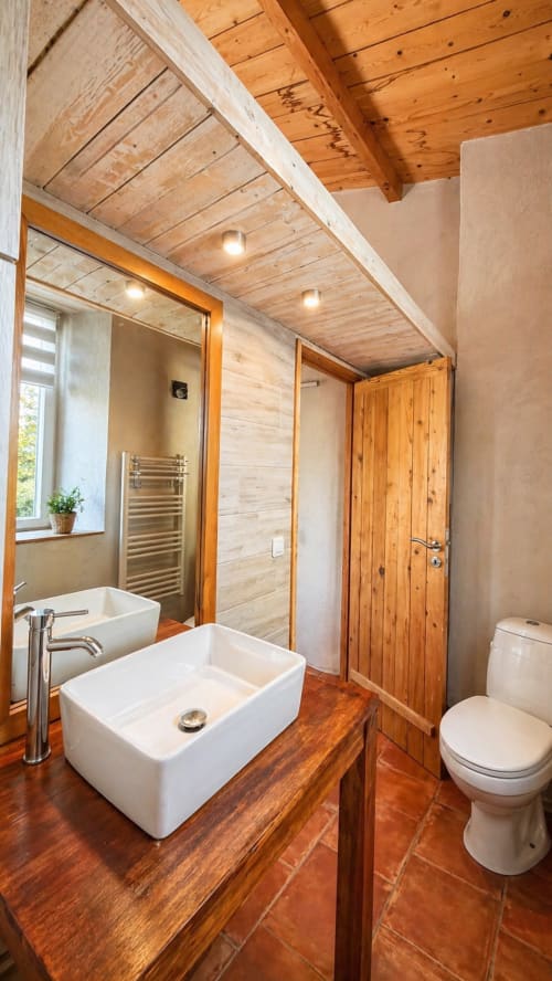 Salle de bains moderne de la villa Le Maquis Plage avec plafond en bois, vasque blanche, toilettes et douche