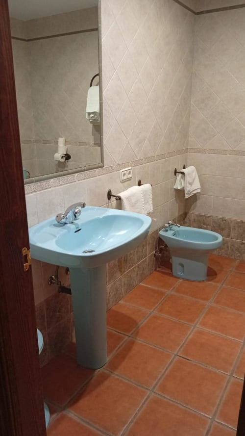 Hotel Mulhacén Trevélez Suite bathroom with pedestal sink, bidet, and terracotta tile flooring