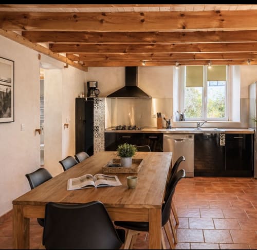 Cuisine ouverte et salle à manger contemporaines au Maquis Plage avec poutres en bois, mobilier noir et carrelage en terre cuite