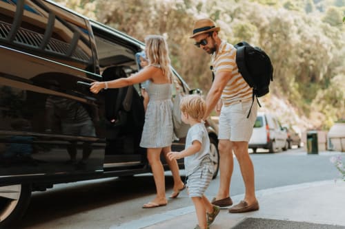 Family loading SUV at LH51 Rooms and Apartments, Italy. Parents and children preparing for road trip near accommodation.