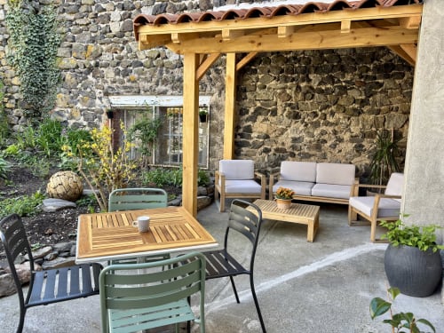 Terrasse extérieure de l'auberge En si bon chemin à Le Monastier avec mobilier en bois, pergola et murs en pierre