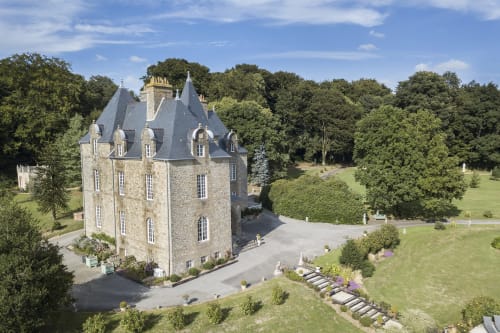 Château de Montbrault, forteresse en pierre avec tourelles entourée de jardins entretenus et d'arbres à Fleurigné, France