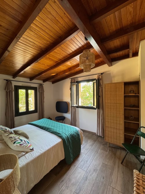 Chambre moderne à la Maison Terre de Lune à Mondragon avec poutres apparentes, lit queen-size et vue sur la piscine