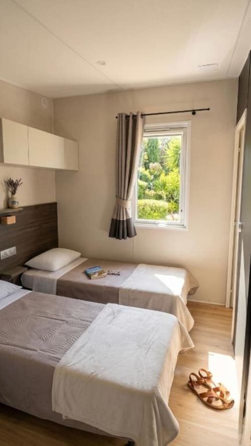 Modern twin bedroom at Le Maquis Plage with twin beds, wooden furnishings, and garden view window in Poggio-Mezzana