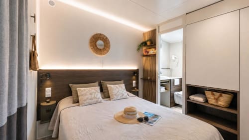 Chambre d'hôtel moderne au Maquis Plage avec tête de lit sombre, salle de bains attenante et touches décoratives en tissage