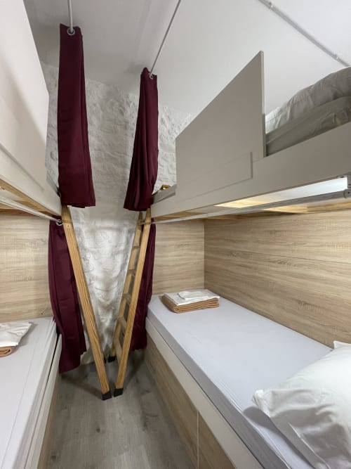 Shared mixed dorm room with four bunk beds at Therma Pilgrim Hostel in Caldas de Reis, burgundy privacy curtains