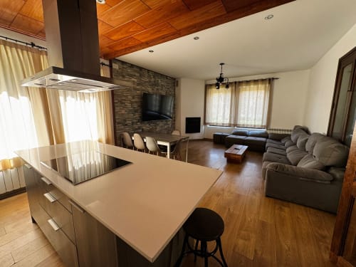 Interior de villa diàfana a El Niu de l'Aguila amb moderna illa de cuina, zona de descans i sala d'estar amb acabat de pedra